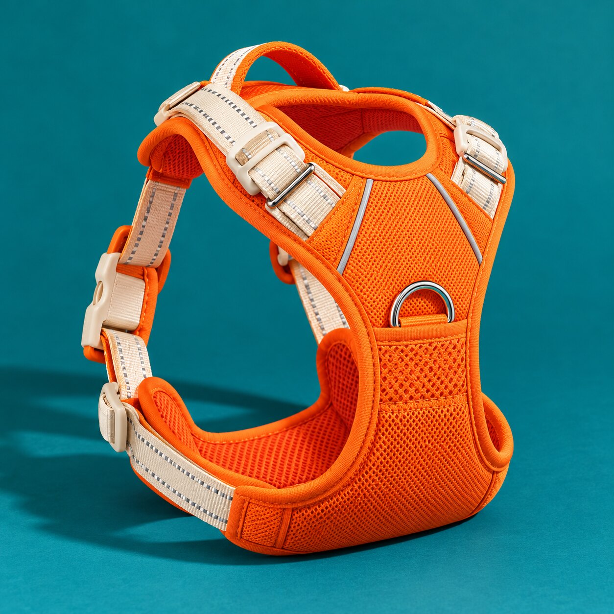 An orange padded dog harness with cream straps on teal